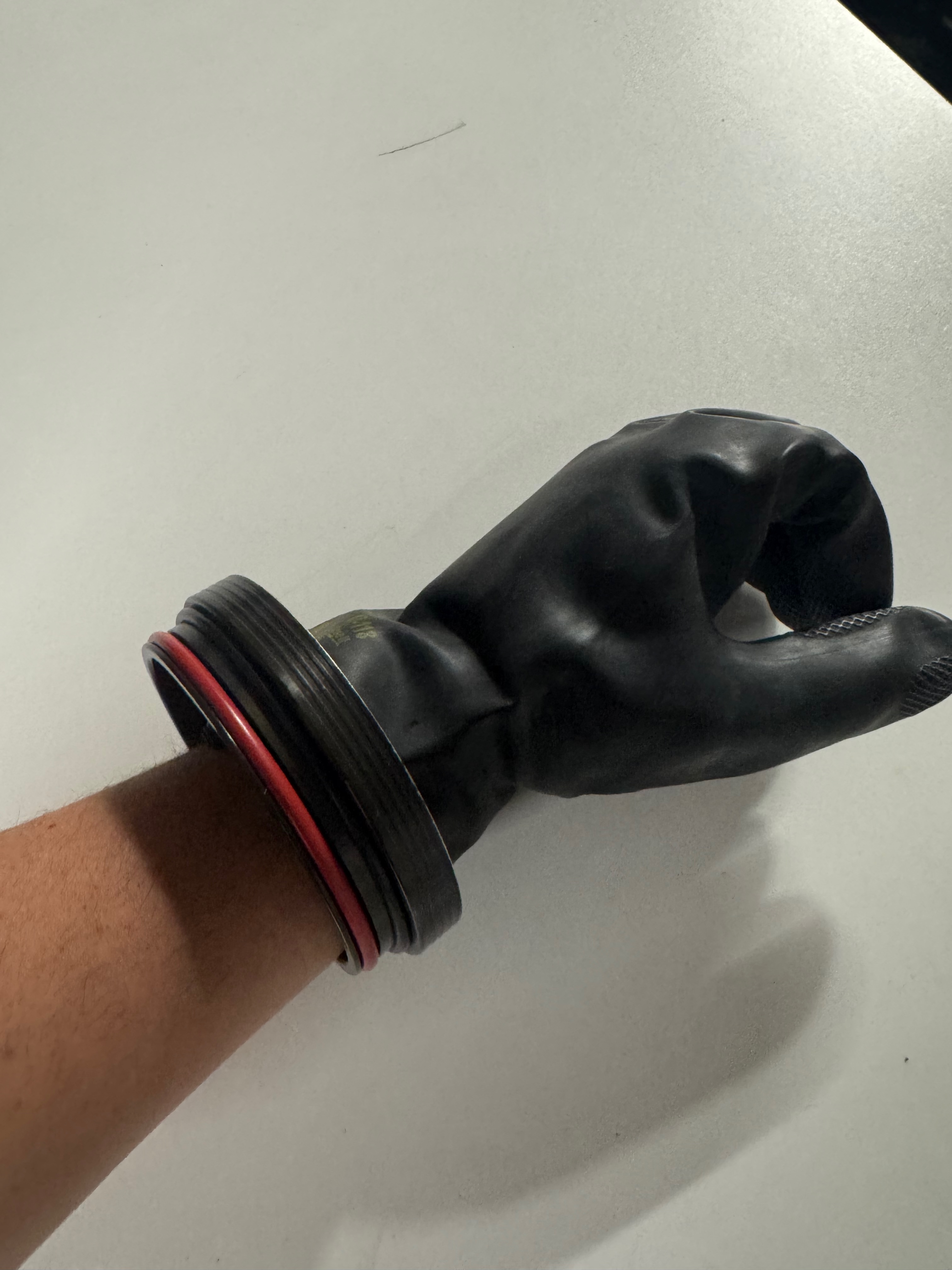 Finished Kubi glove assembly on a wrist — red o-ring seated, glove folded neatly over the ring