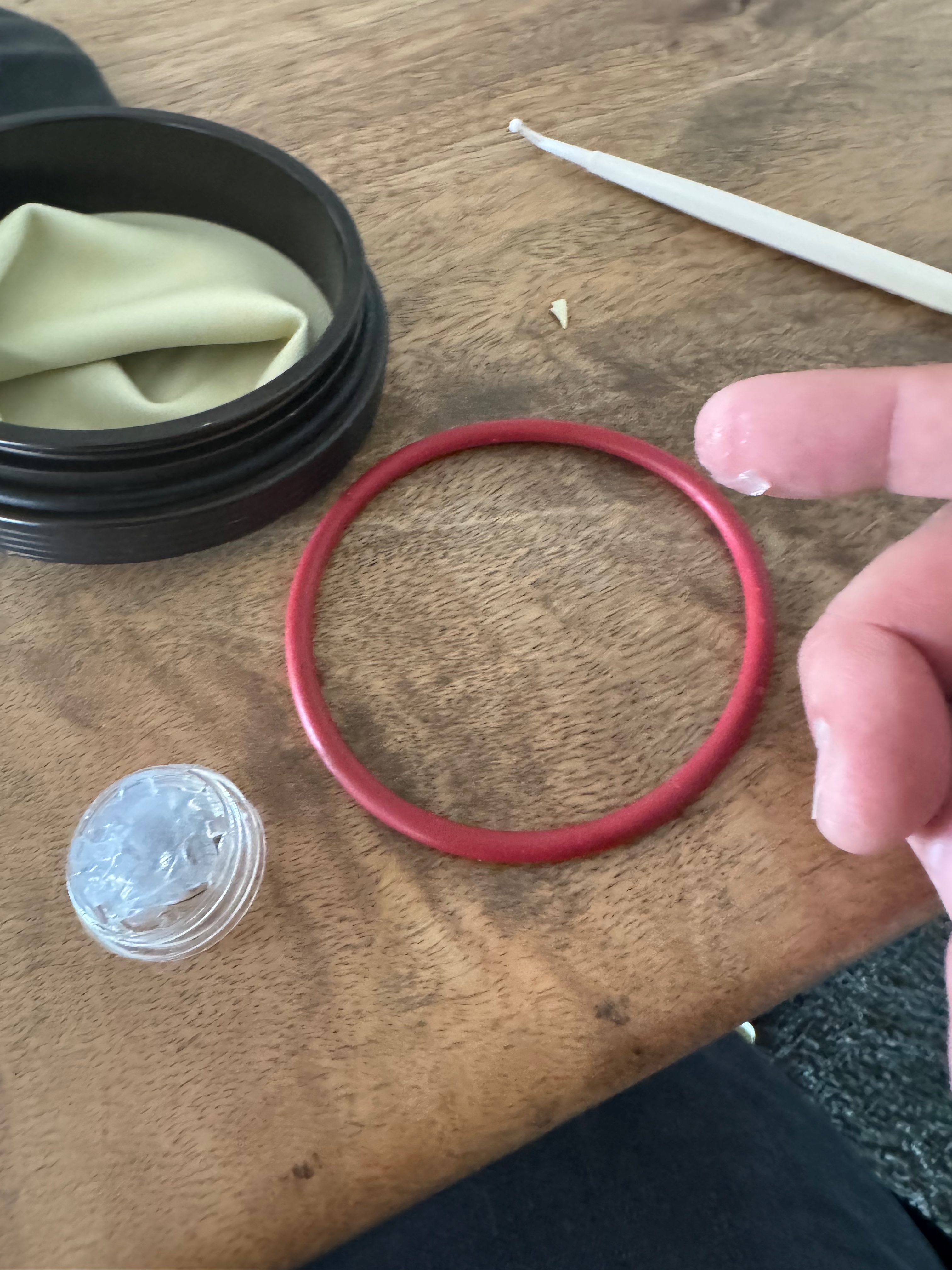 Red Kubi o-ring laid on the workbench next to a pot of silicone grease and a cleaning cloth